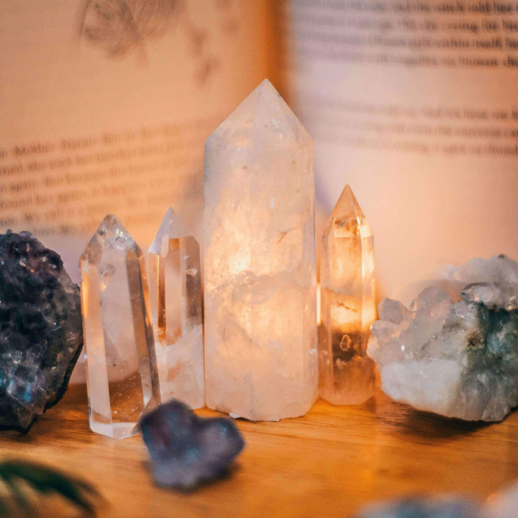 A set of healing crystals arranged on a table with an open book in the background