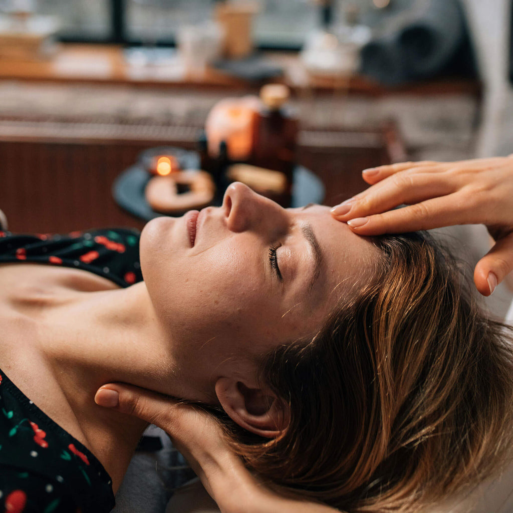 Woman receiving a Theta Healing session in a serene setting, surrounded by soft candlelight and calming energy.